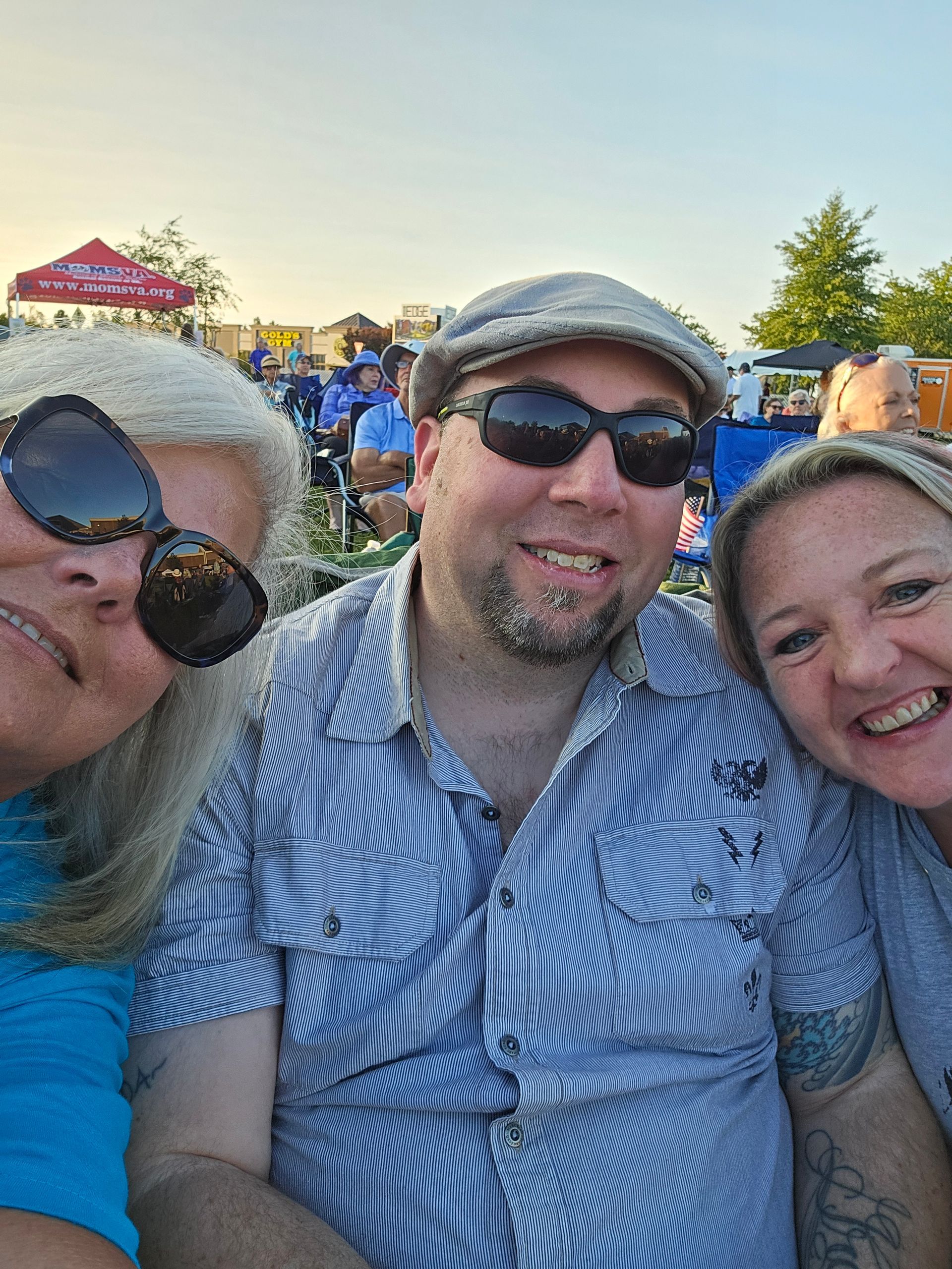 A man and two women are posing for a picture at a concert.