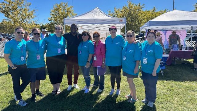 A group of people wearing blue shirts are posing for a picture.