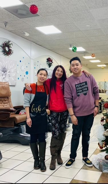 Three people are posing for a picture in a nail salon.