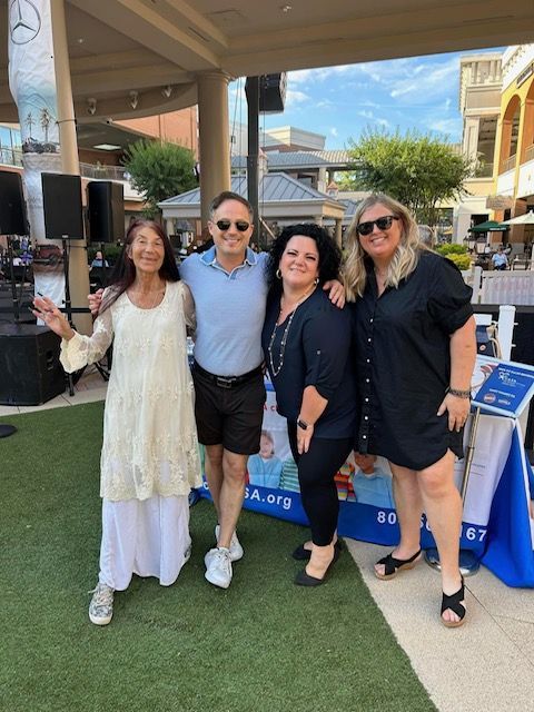 A group of people posing for a picture in front of a mercedes sign