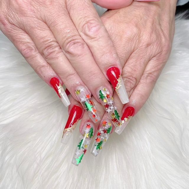 A woman 's nails are decorated with christmas trees and stars.