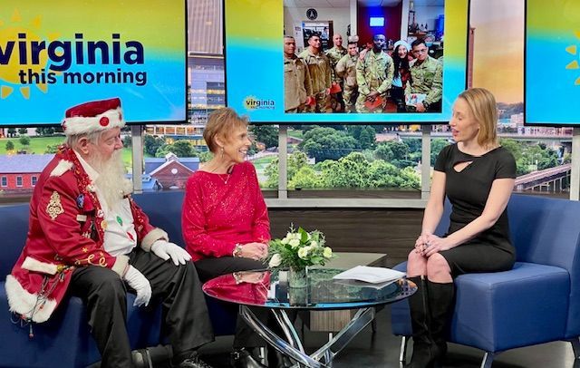 A man dressed as santa claus is sitting on a couch with two women.