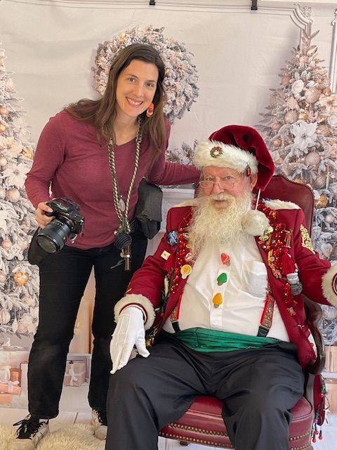 A woman is standing next to a man dressed as santa claus