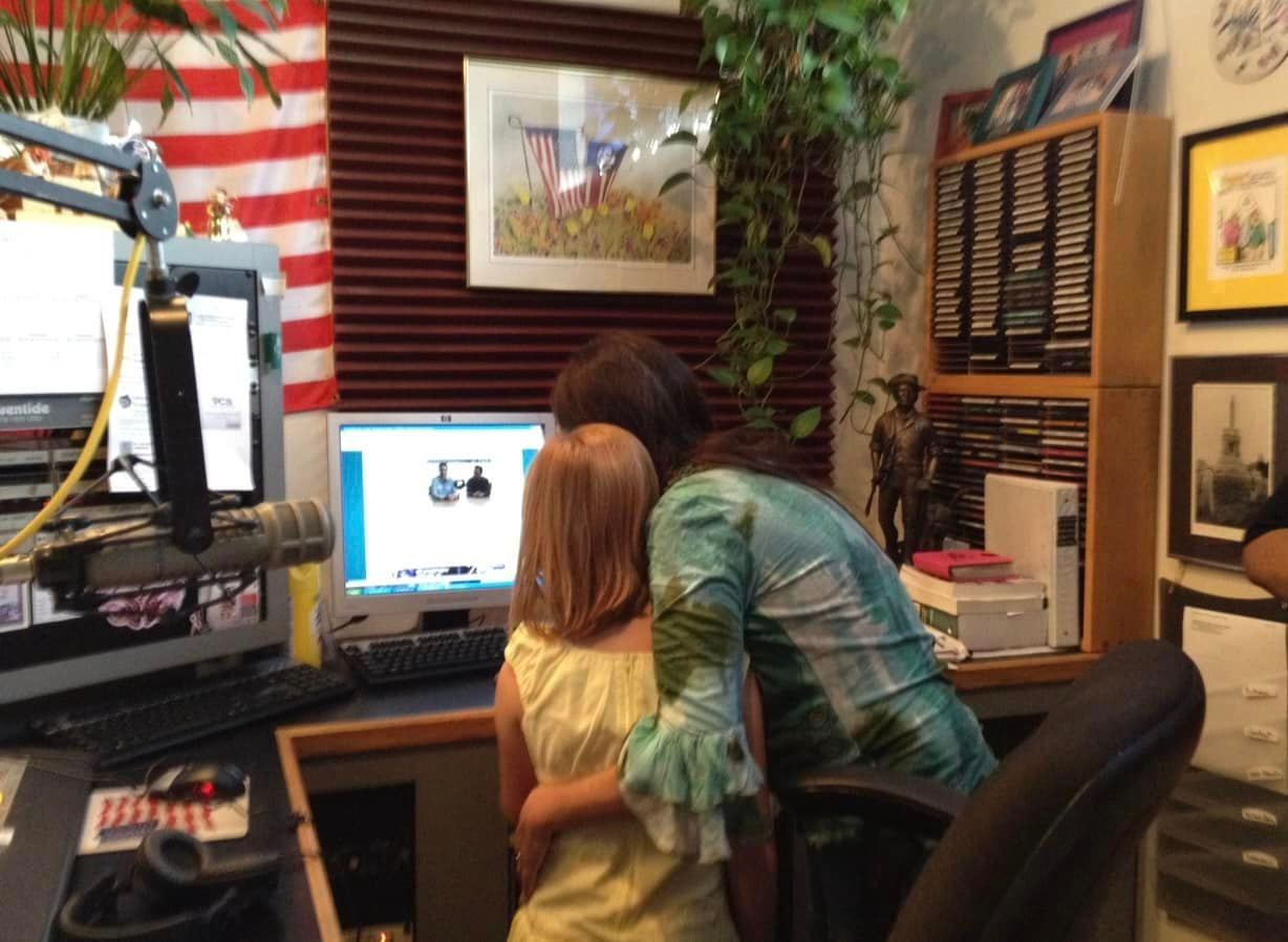 A woman hugging a little girl in front of a computer