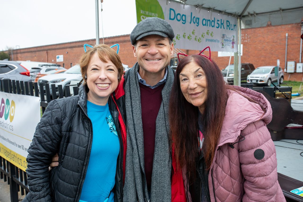 A man and two women are posing for a picture in front of a tent.