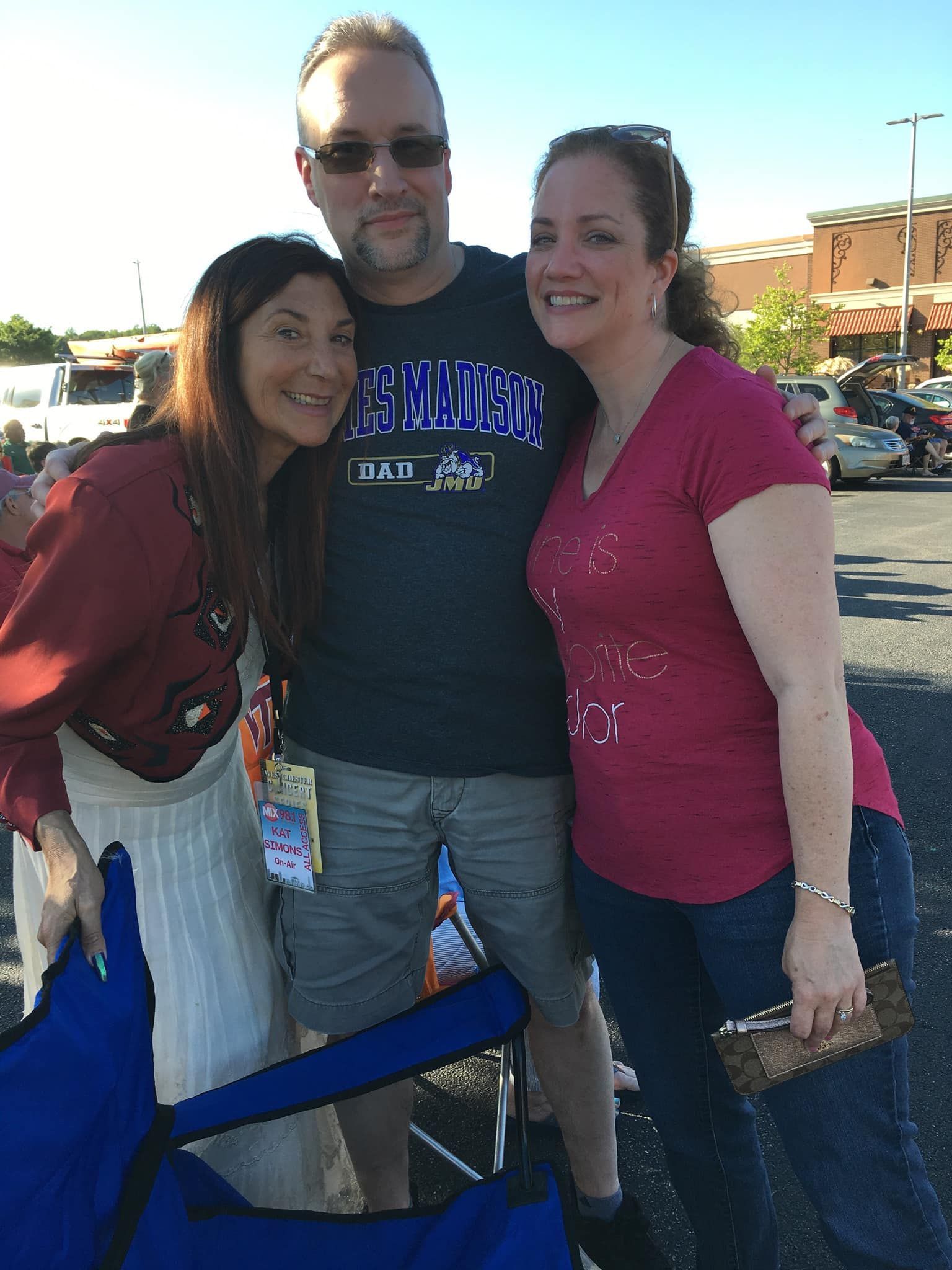A man and two women are posing for a picture in a parking lot.