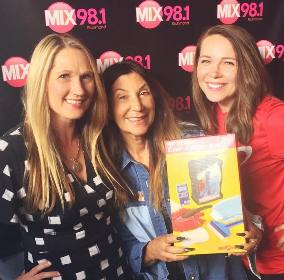 Three women standing in front of a wall that says mix 98.1