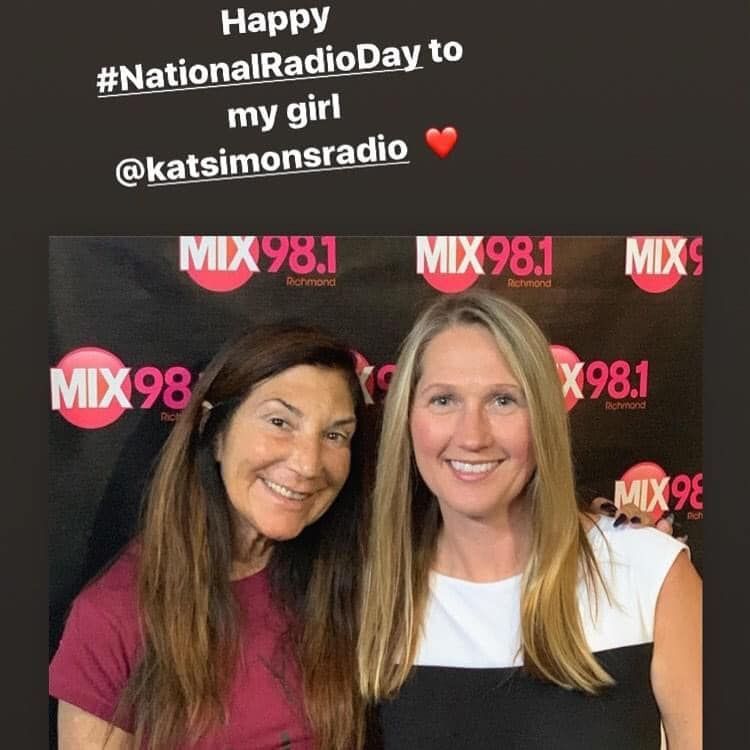 Two women standing in front of a sign that says mix 98.1