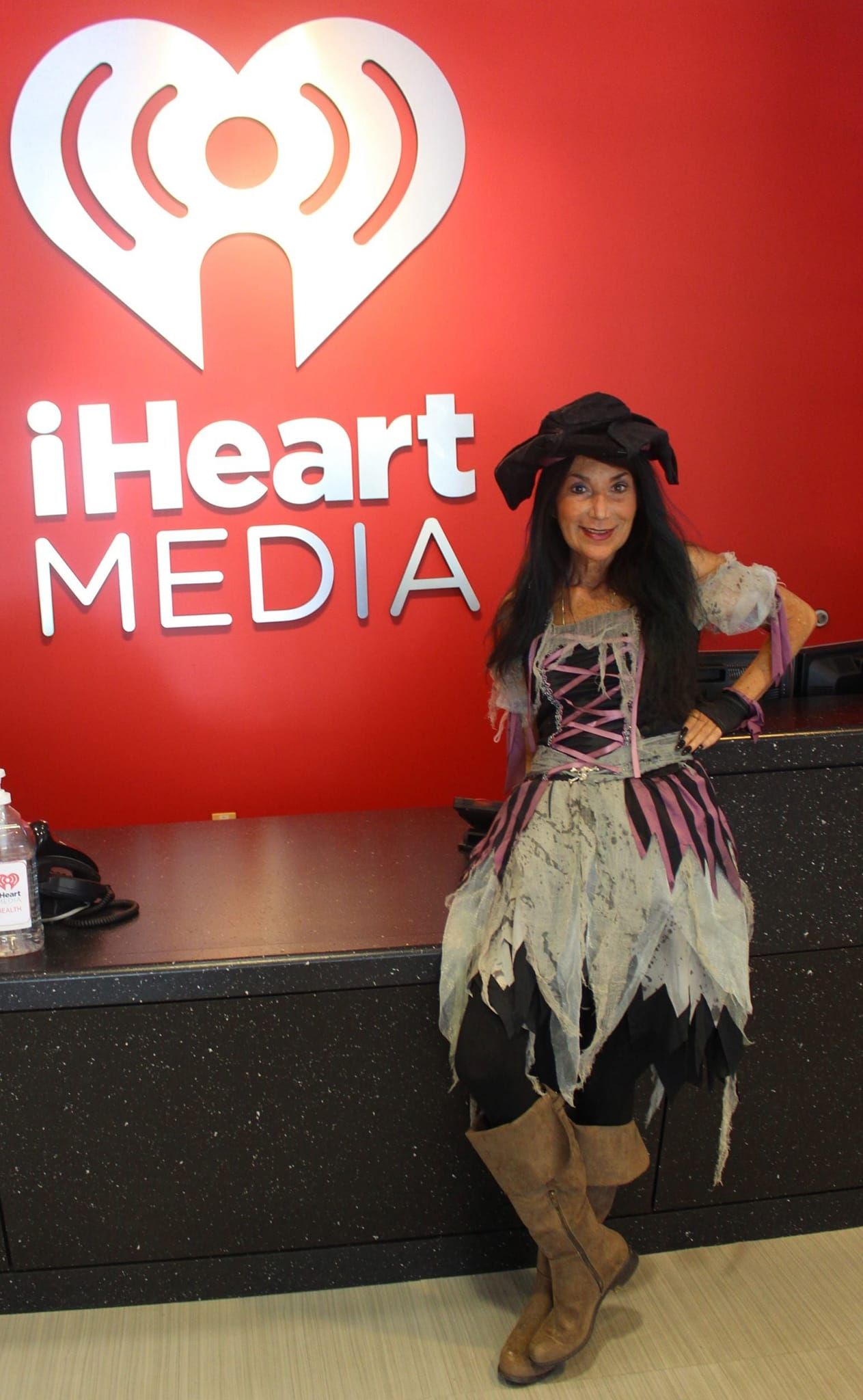 A woman in a pirate costume stands in front of an iheart media sign