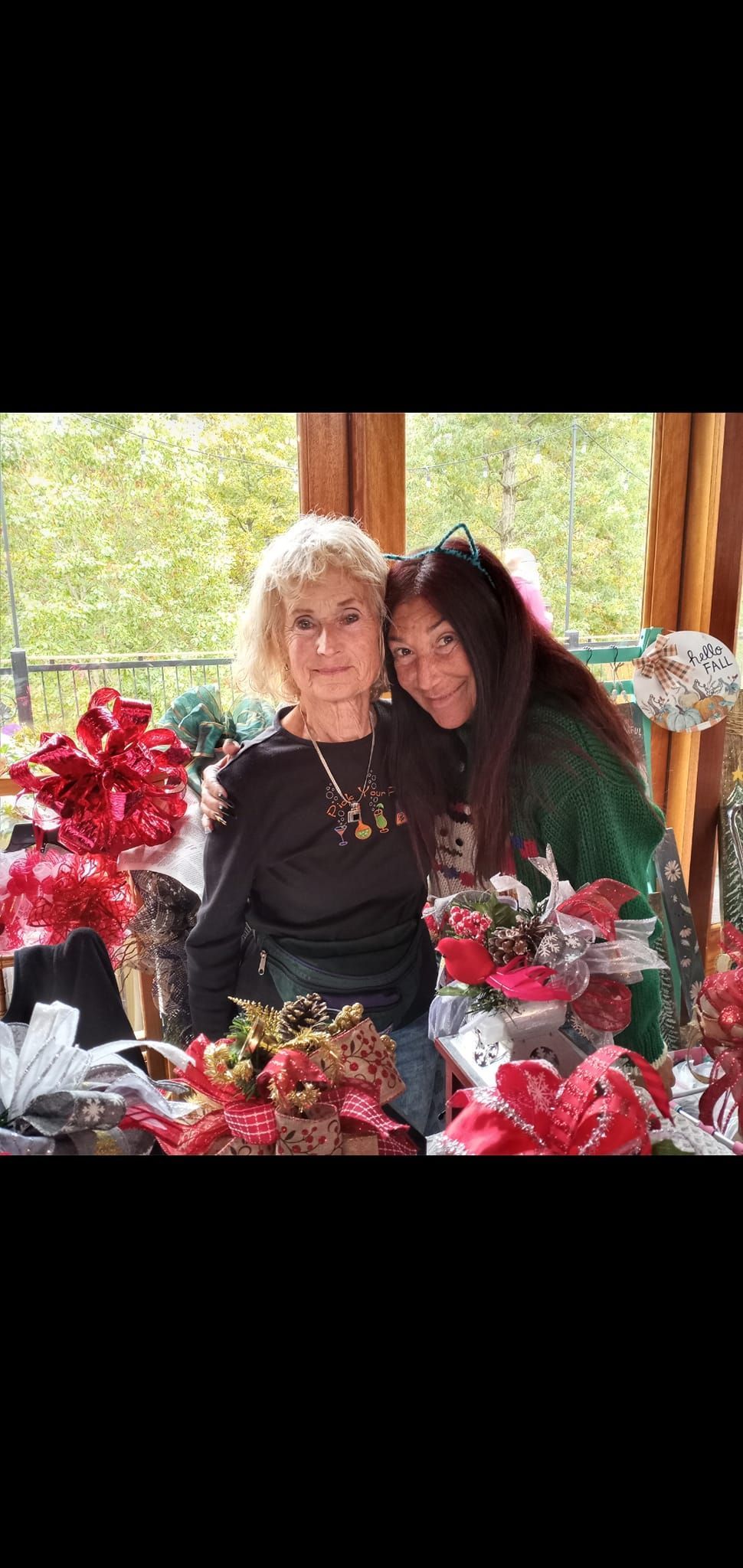 Two women are sitting next to each other in a room with christmas decorations.