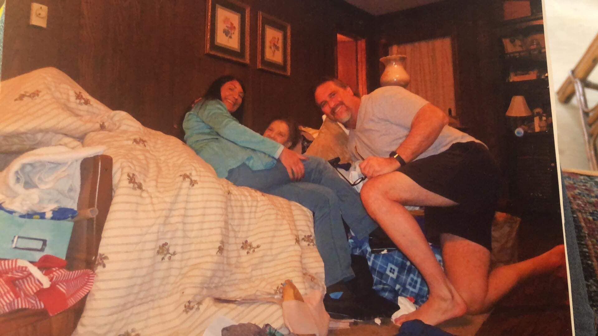 A man is kneeling down next to a woman laying on a bed.