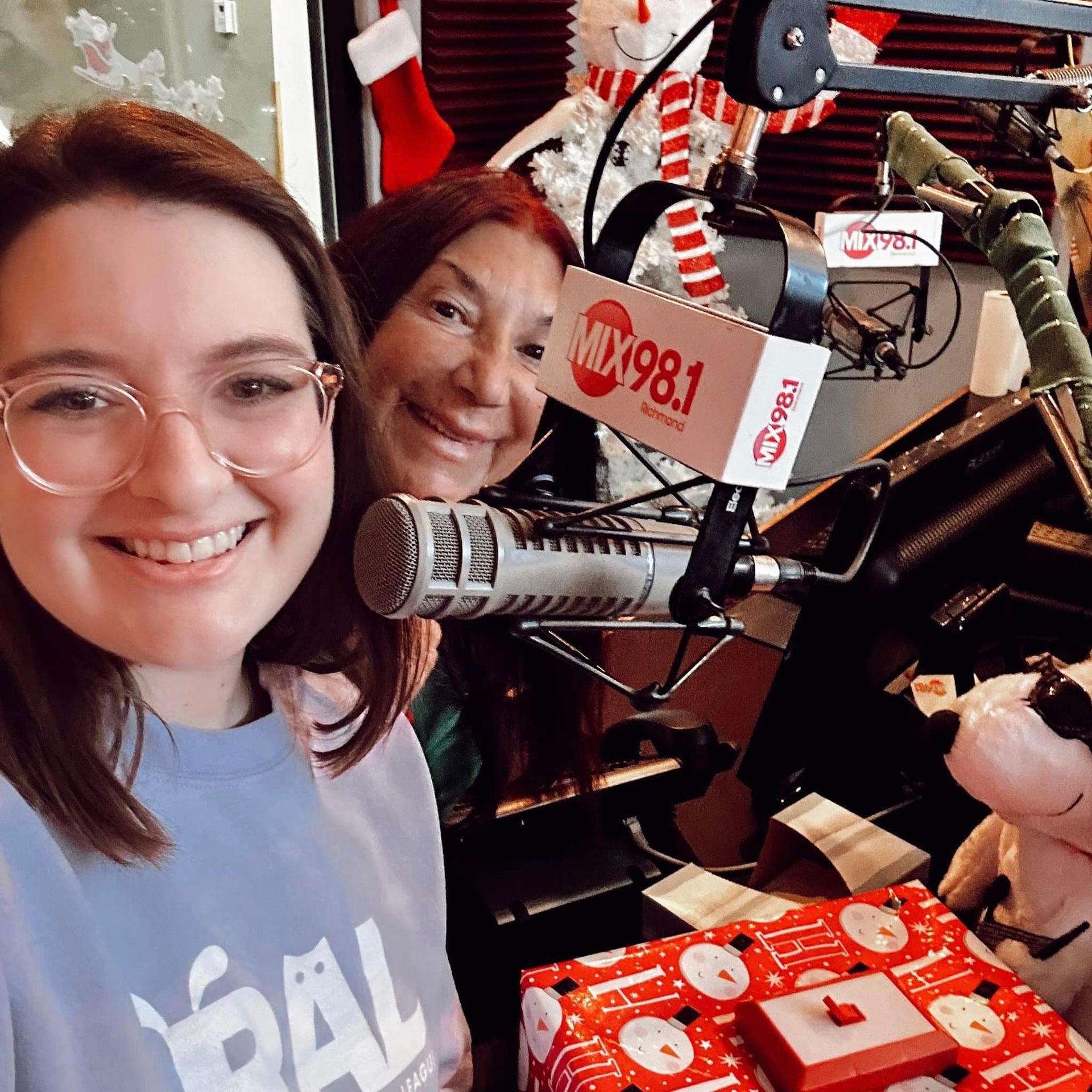 Two women are posing for a picture in front of a microphone.