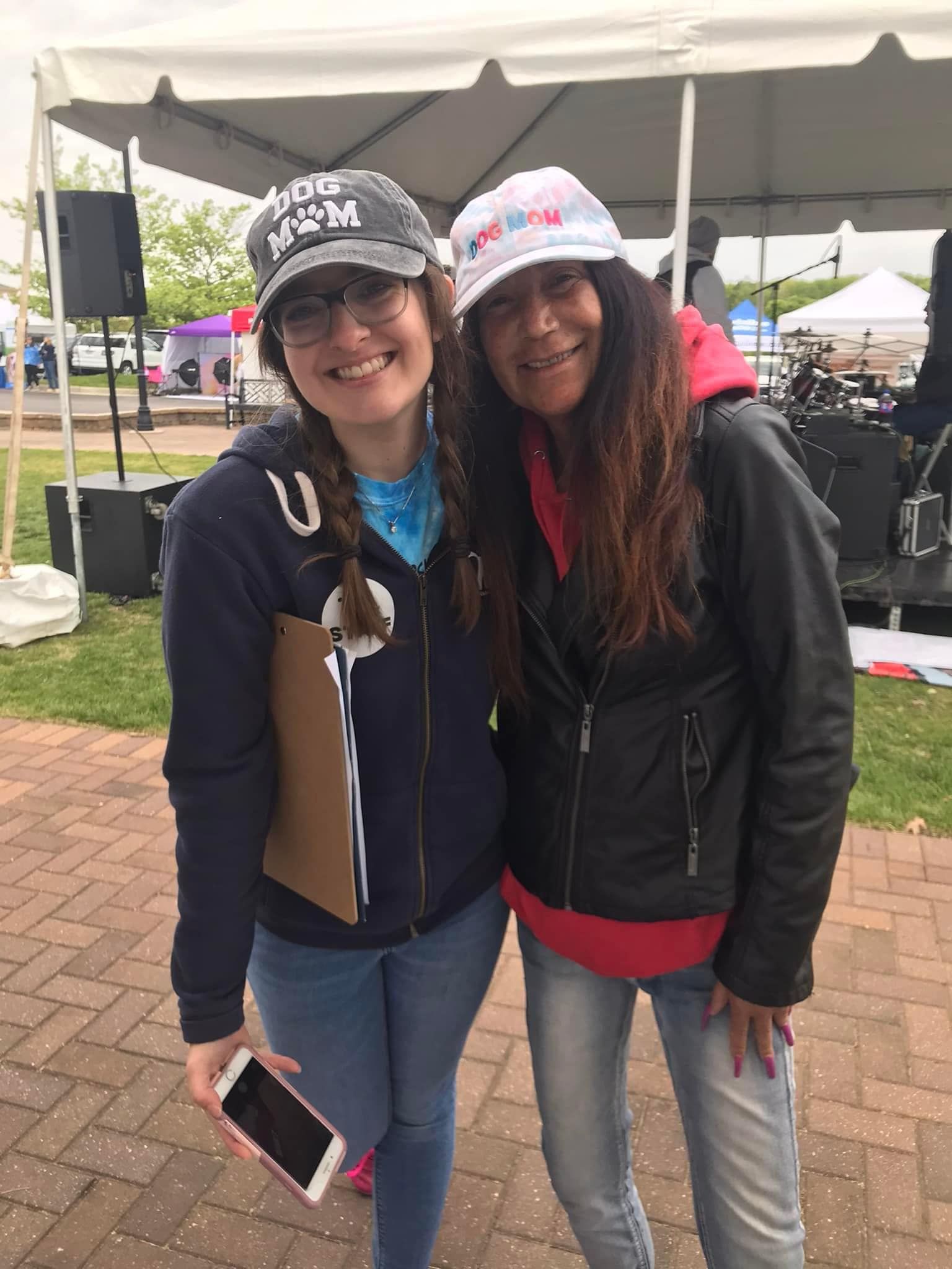 Two women are posing for a picture in front of a tent.