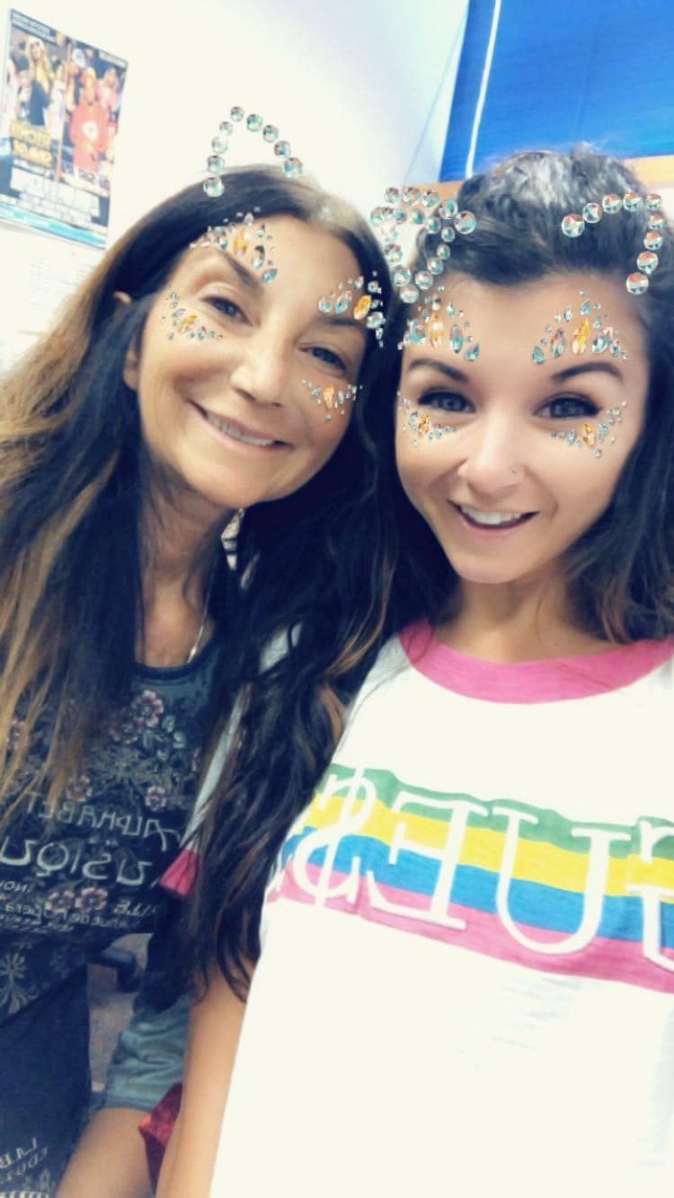 A woman and a girl are posing for a picture with glitter on their faces.