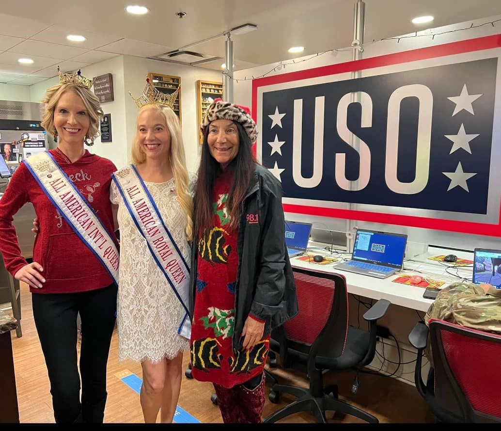 Three women are posing for a picture in front of a uso sign.