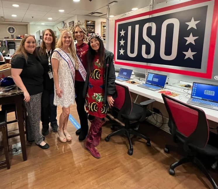 A group of women are posing for a picture in front of a uso sign.