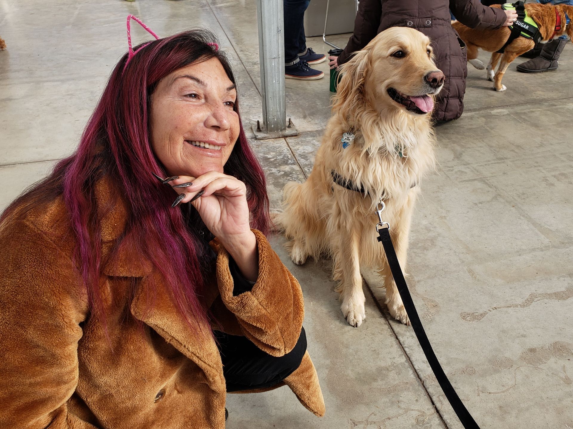 A woman with pink hair is sitting next to a dog on a leash.