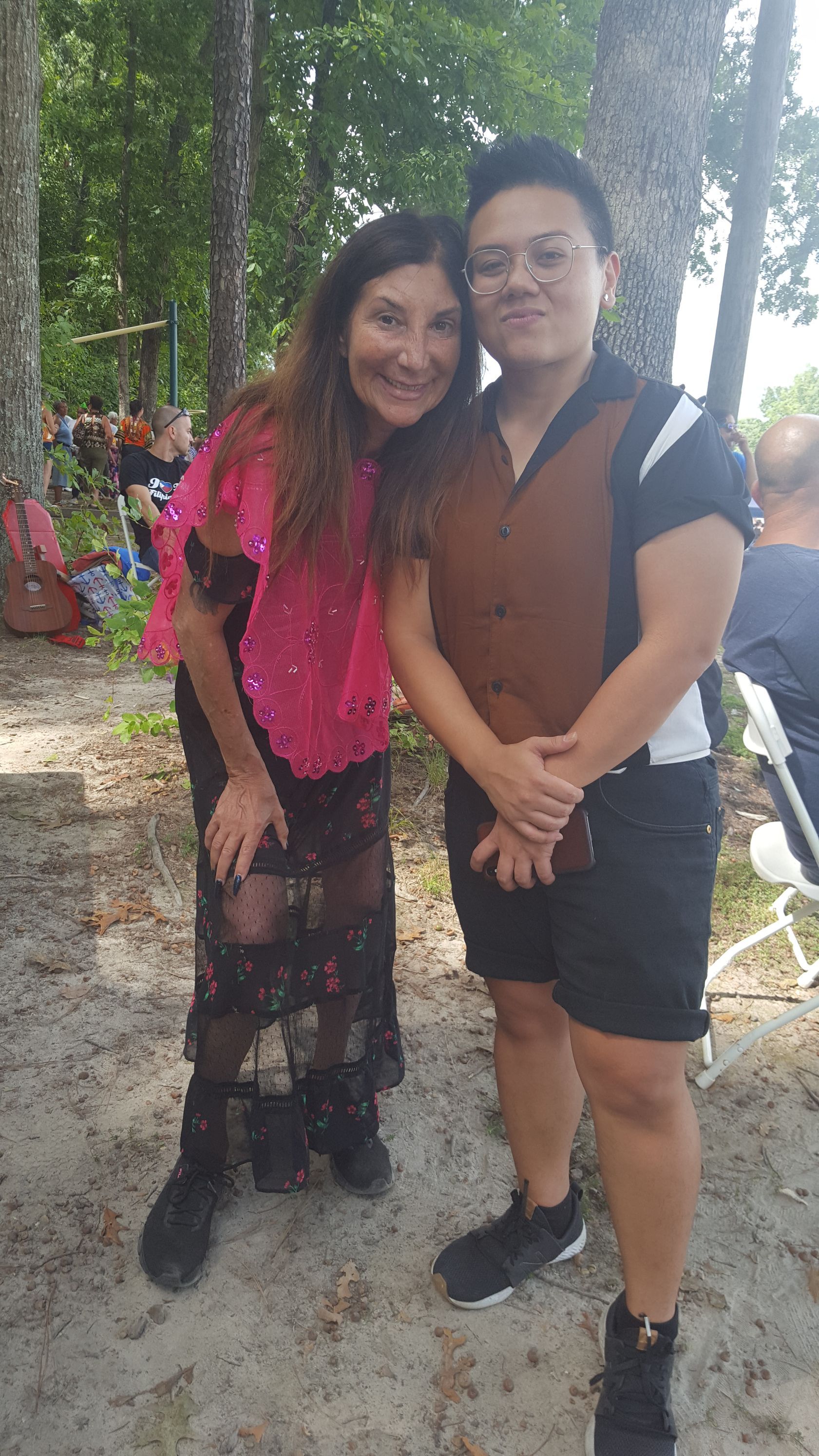 A man and a woman are posing for a picture in the woods.
