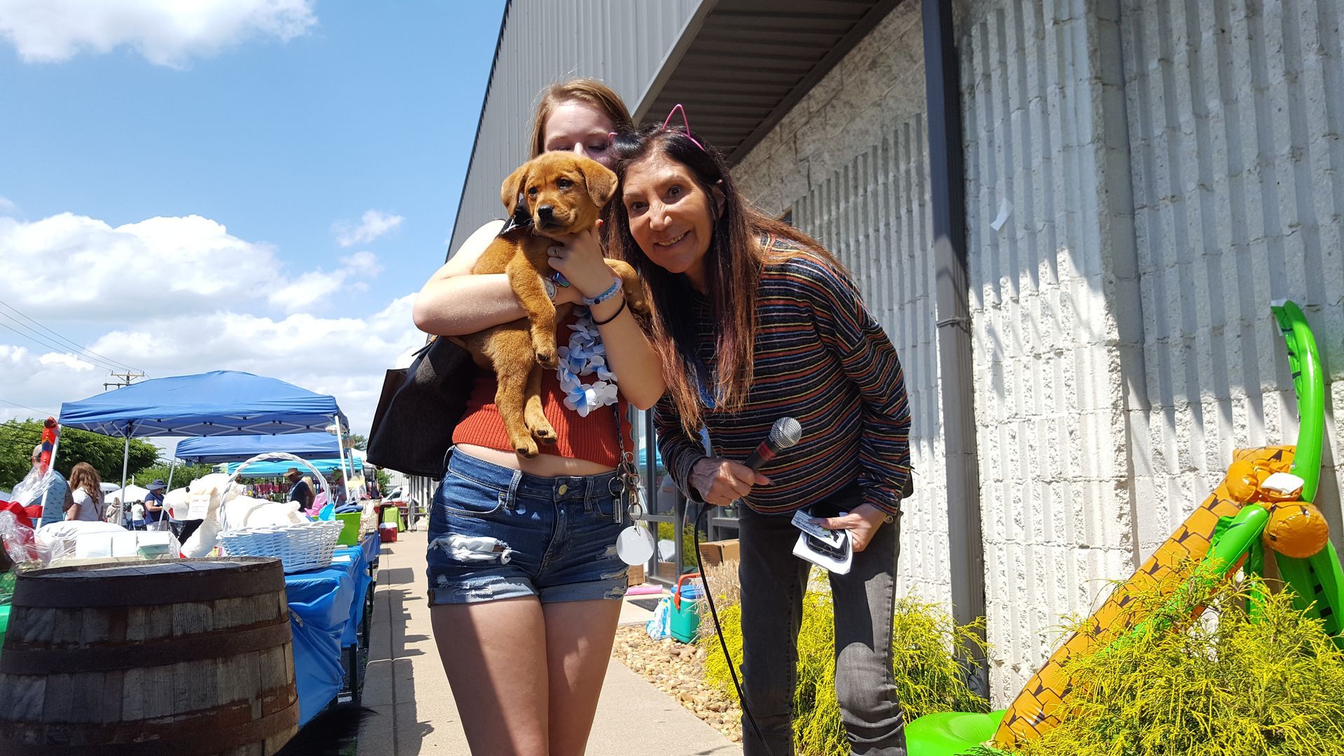 Two women are standing next to each other holding a small dog.