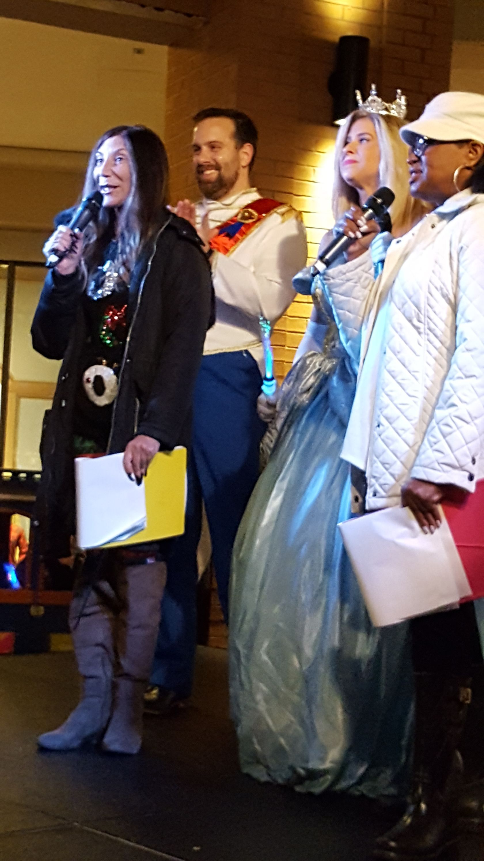 A group of people are standing on a stage holding microphones.