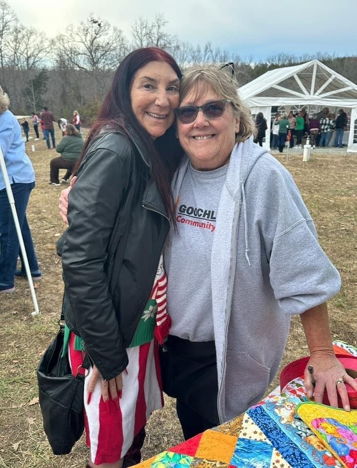Two women are posing for a picture together in a field.