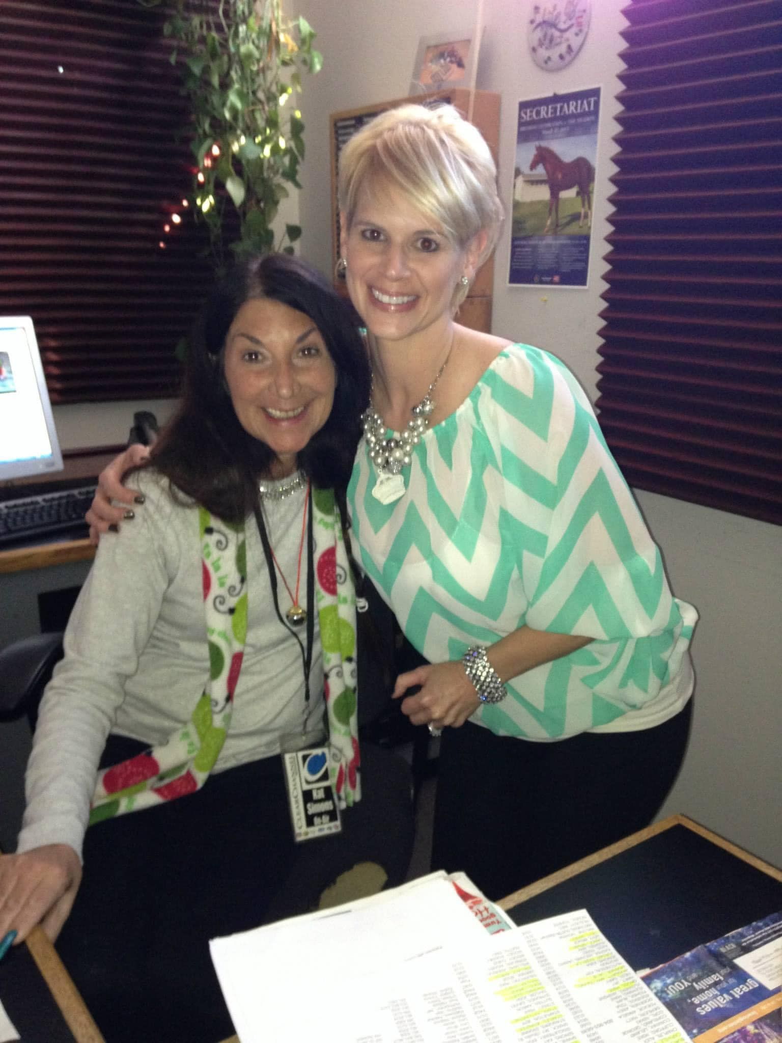 Two women are posing for a picture in a room with a clock on the wall