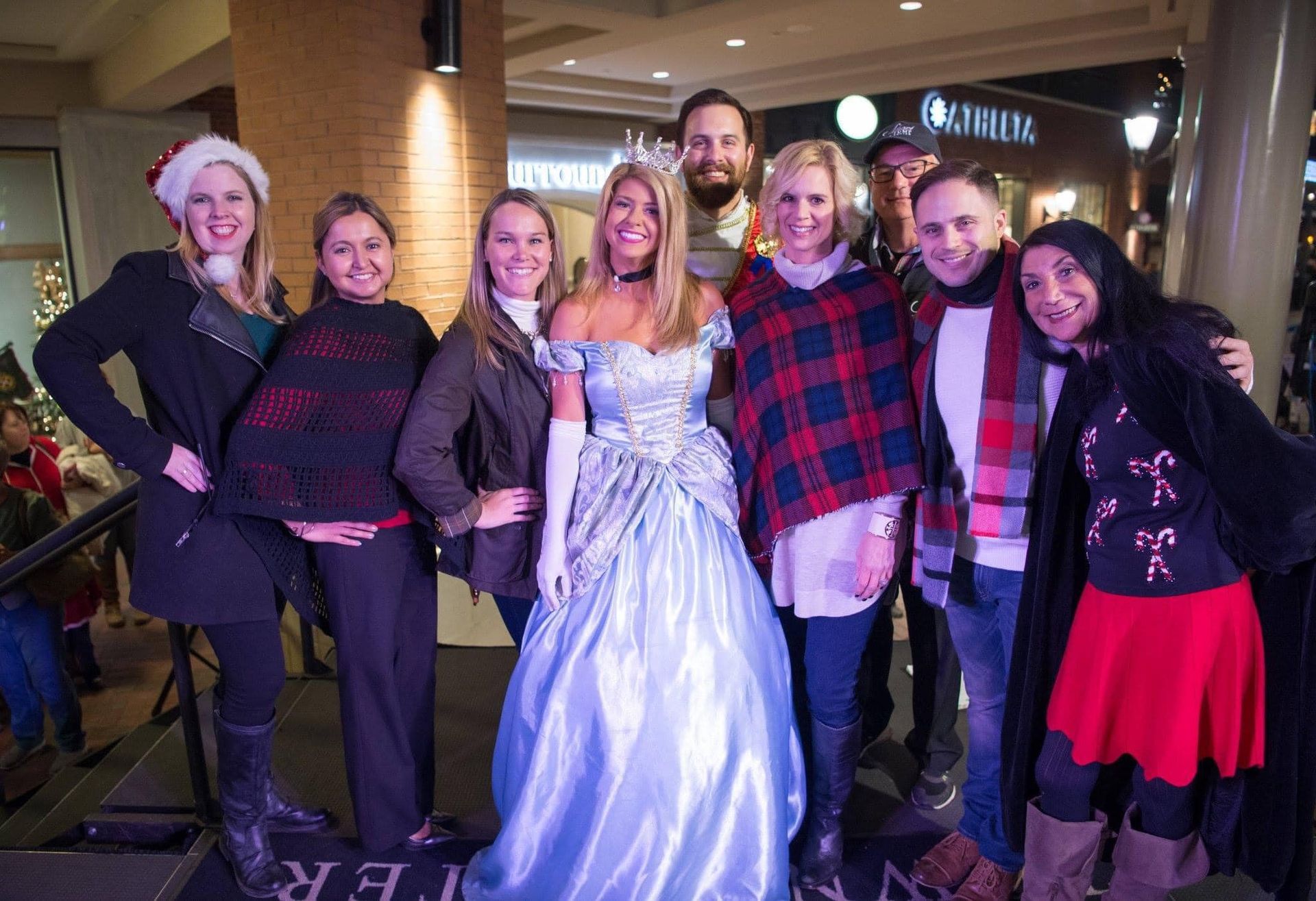 A group of people are posing for a picture with a woman in a cinderella dress.