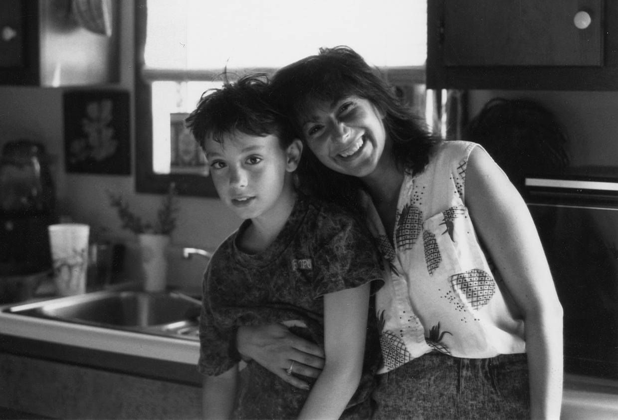 A woman is holding a child in her arms in a kitchen