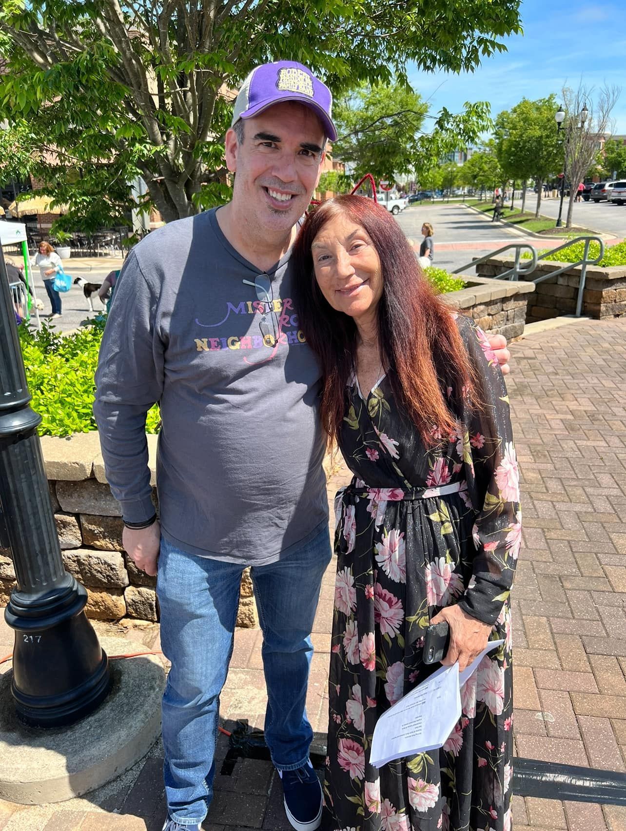 A man and a woman are posing for a picture on a sidewalk.