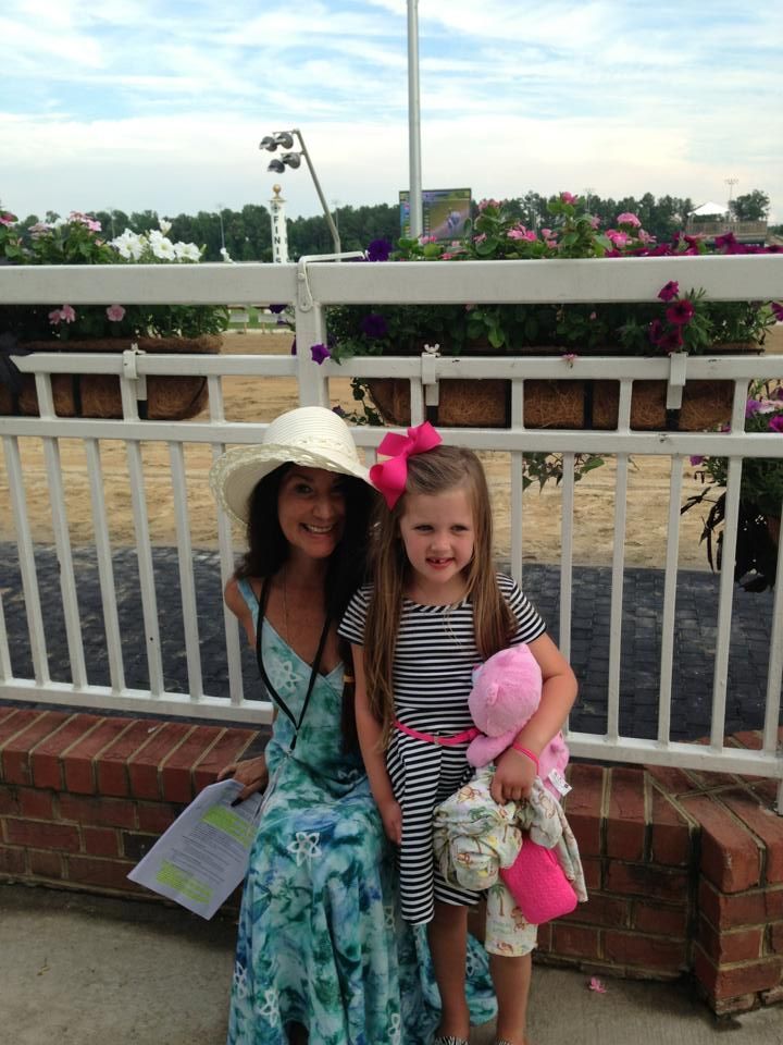 A woman and a little girl are sitting next to each other on a fence.