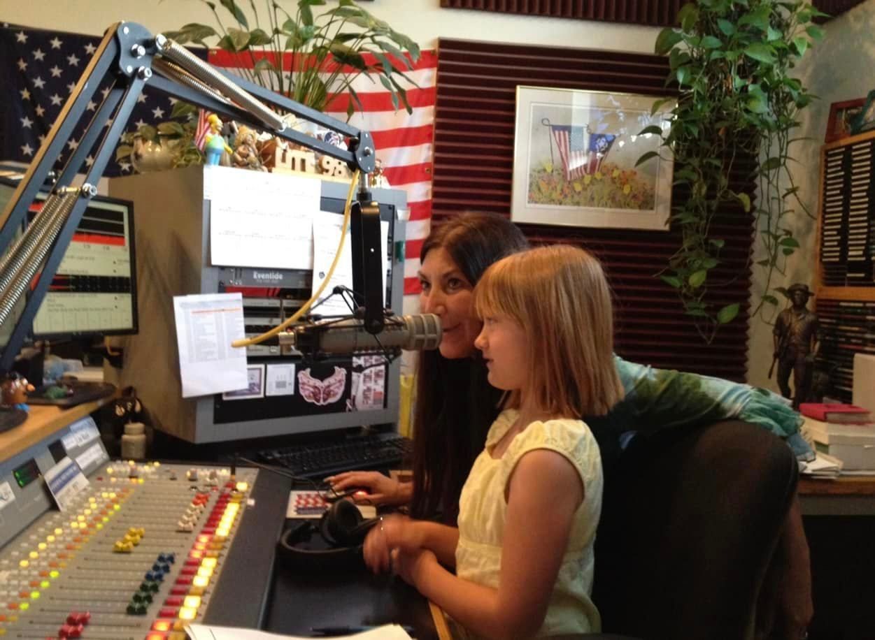 A woman and a little girl are sitting in front of a microphone