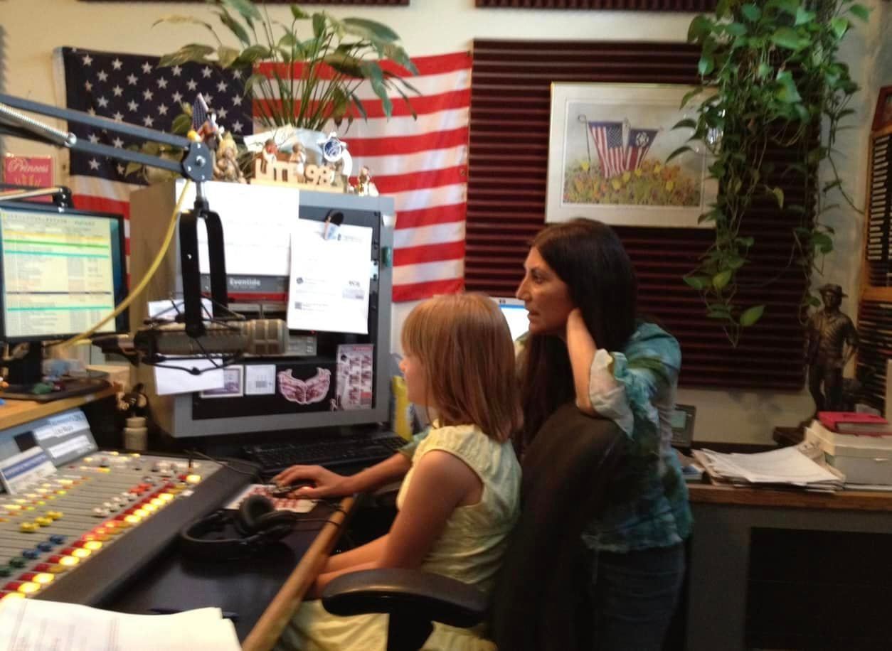 A little girl sits on a woman 's lap in front of a computer