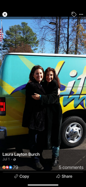 Two women hugging in front of a van that says lift
