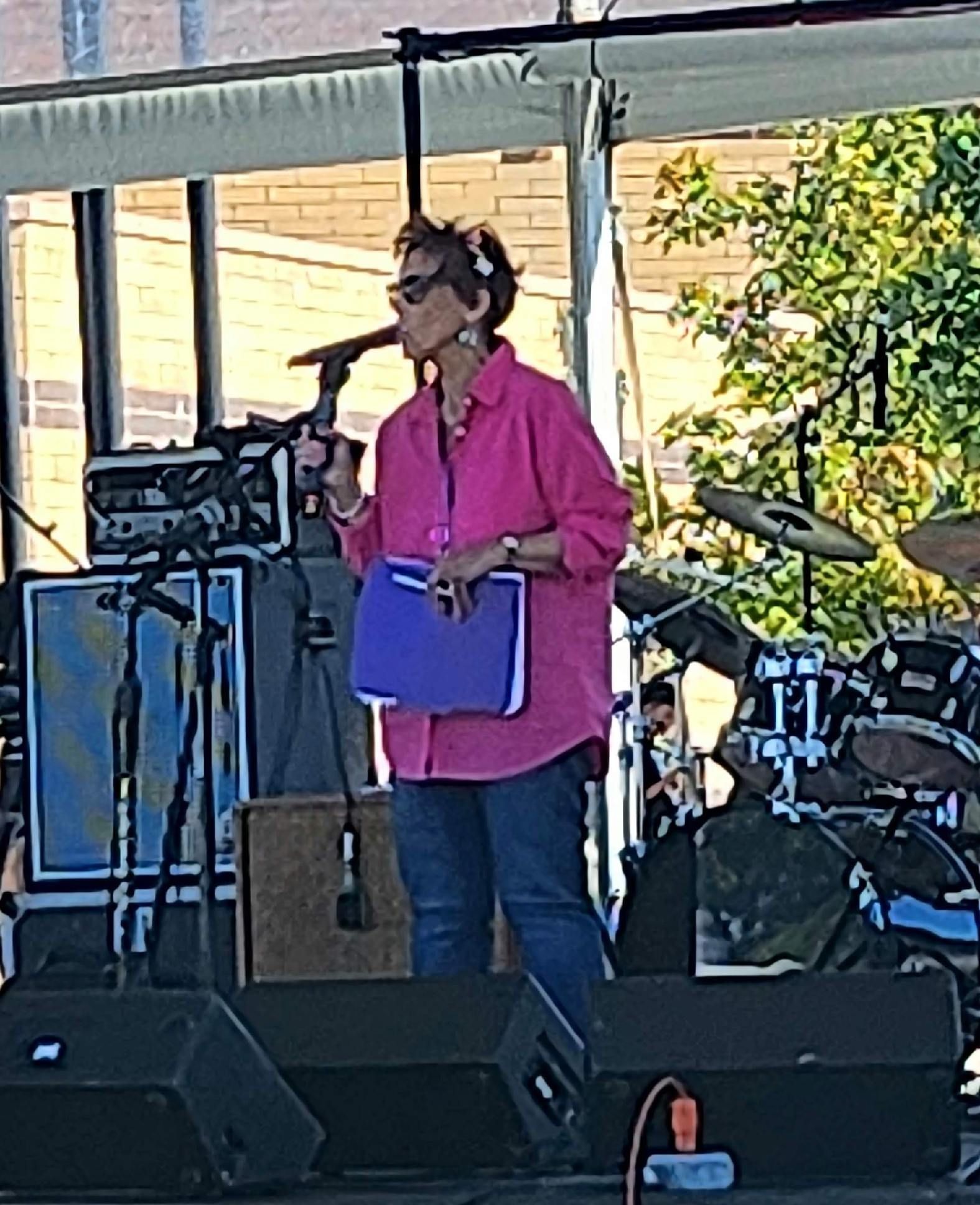 A woman in a pink shirt is singing into a microphone