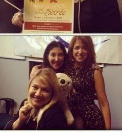 Three women are posing for a picture with a teddy bear.