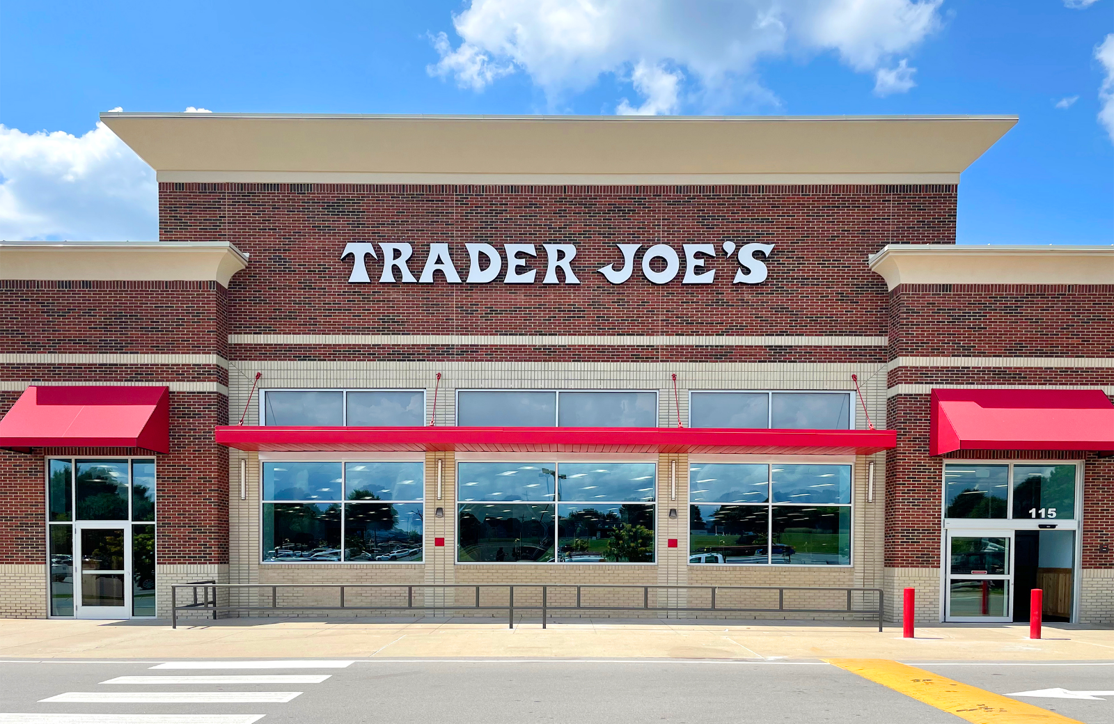 Trader Joe's storefront with red awnings, brick facade, and large windows. Signage reads 