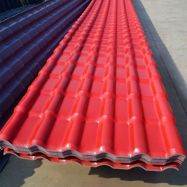 Red corrugated roofing sheets stacked, reflecting light.