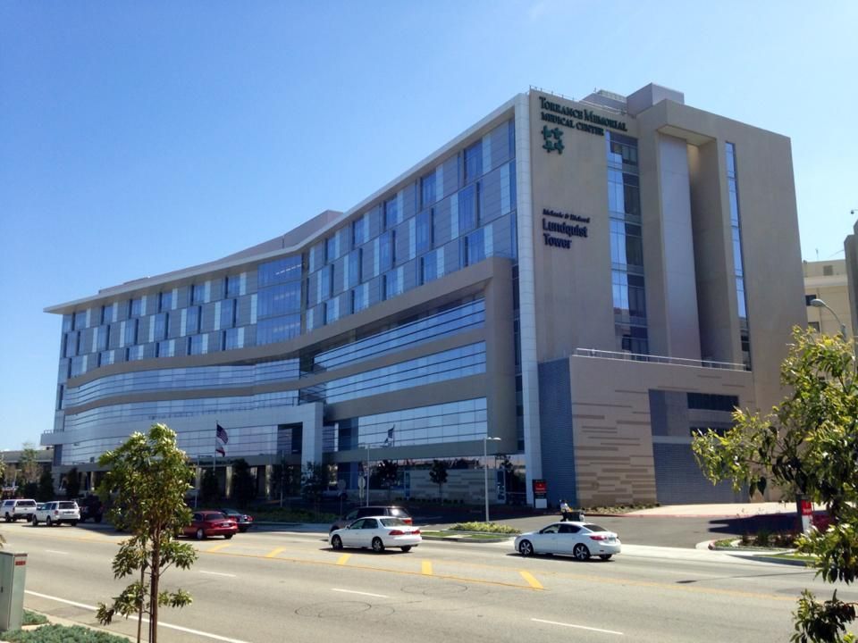 Modern hospital building, with glass and beige facade, sunny day.