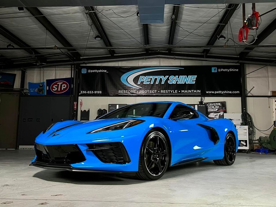 Bright blue sports car inside a garage with Petty Shine banner.