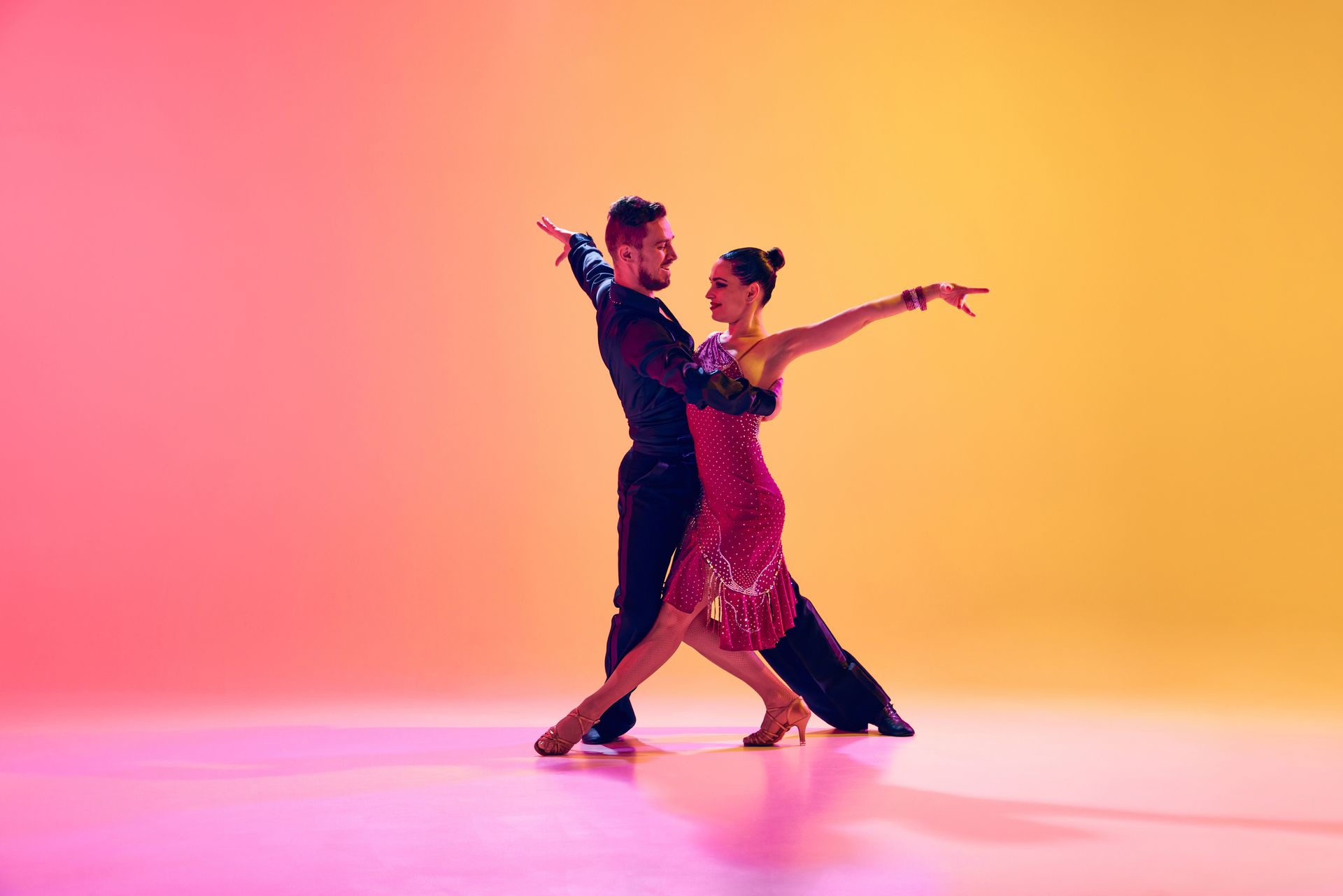 Couple dancing salsa in vibrant red and yellow light.