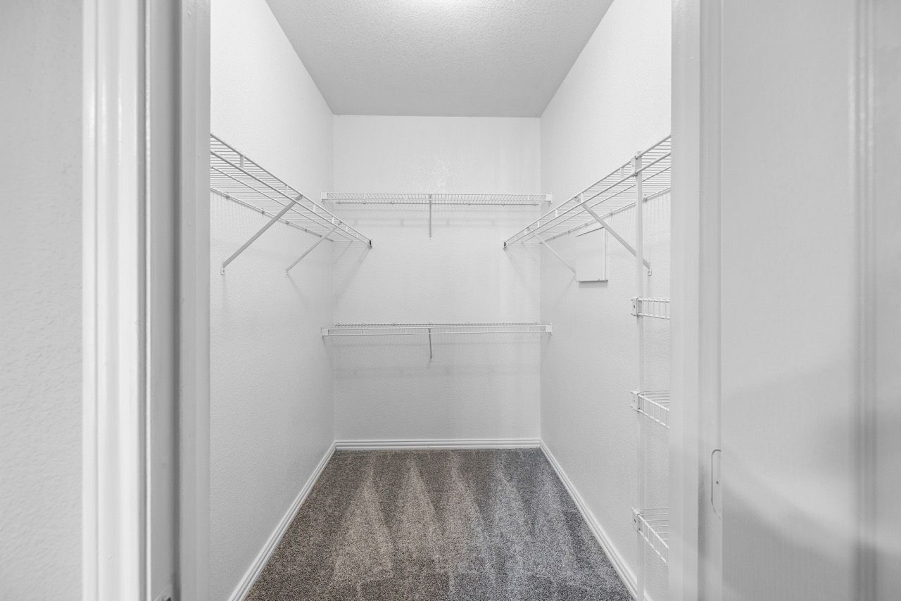 Walk-in closet with white wire shelving and carpeted floor.