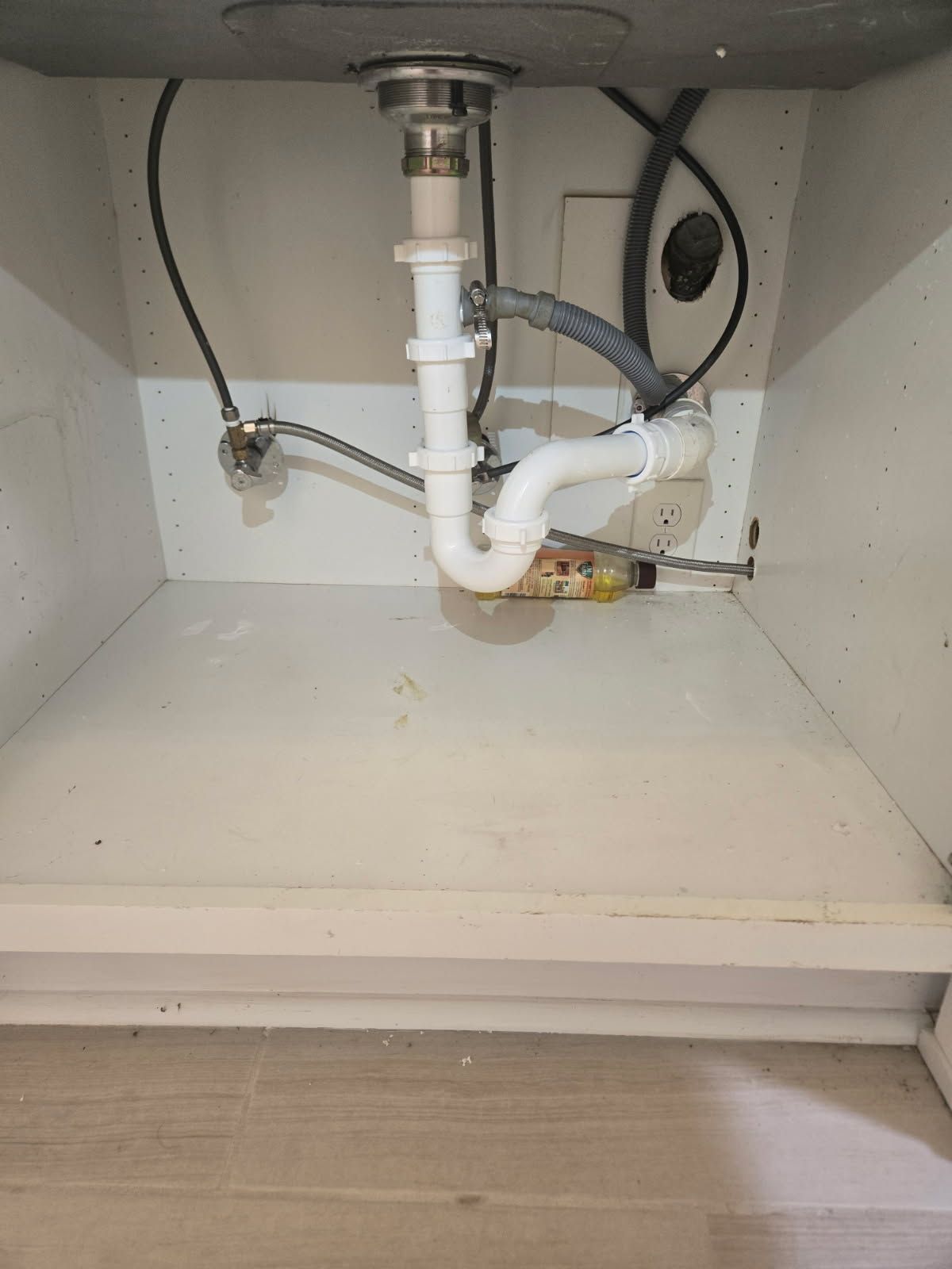 Top-down view of a plumber repairing a stainless steel kitchen sink with tools nearby.