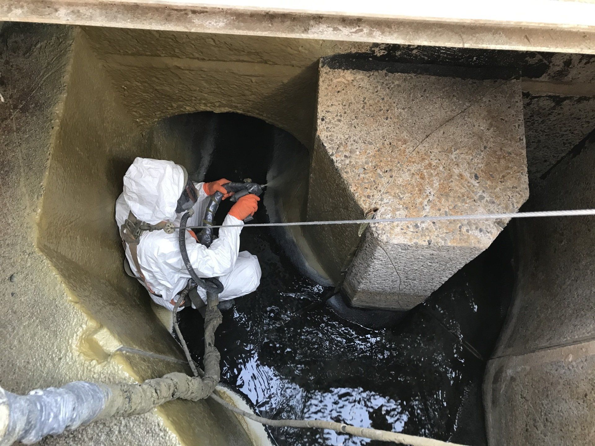 A man in a protective suit is standing in a hole in the ground.