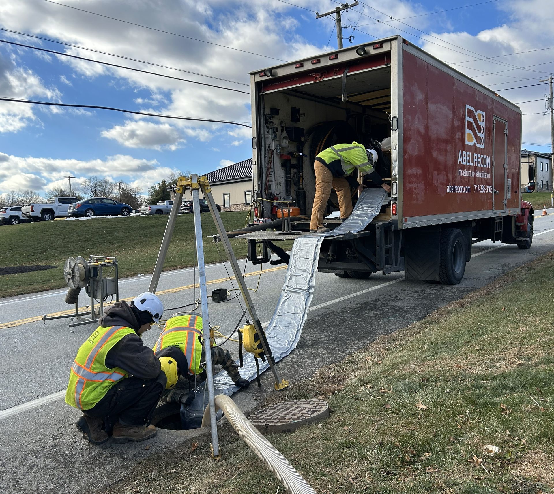 Two men are working on a pipe in front of a truck