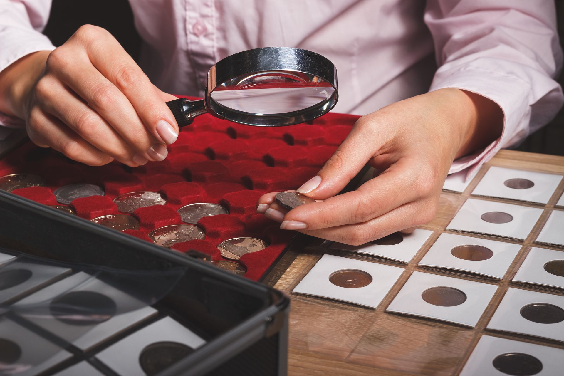 A person is looking at coins with a magnifying glass.