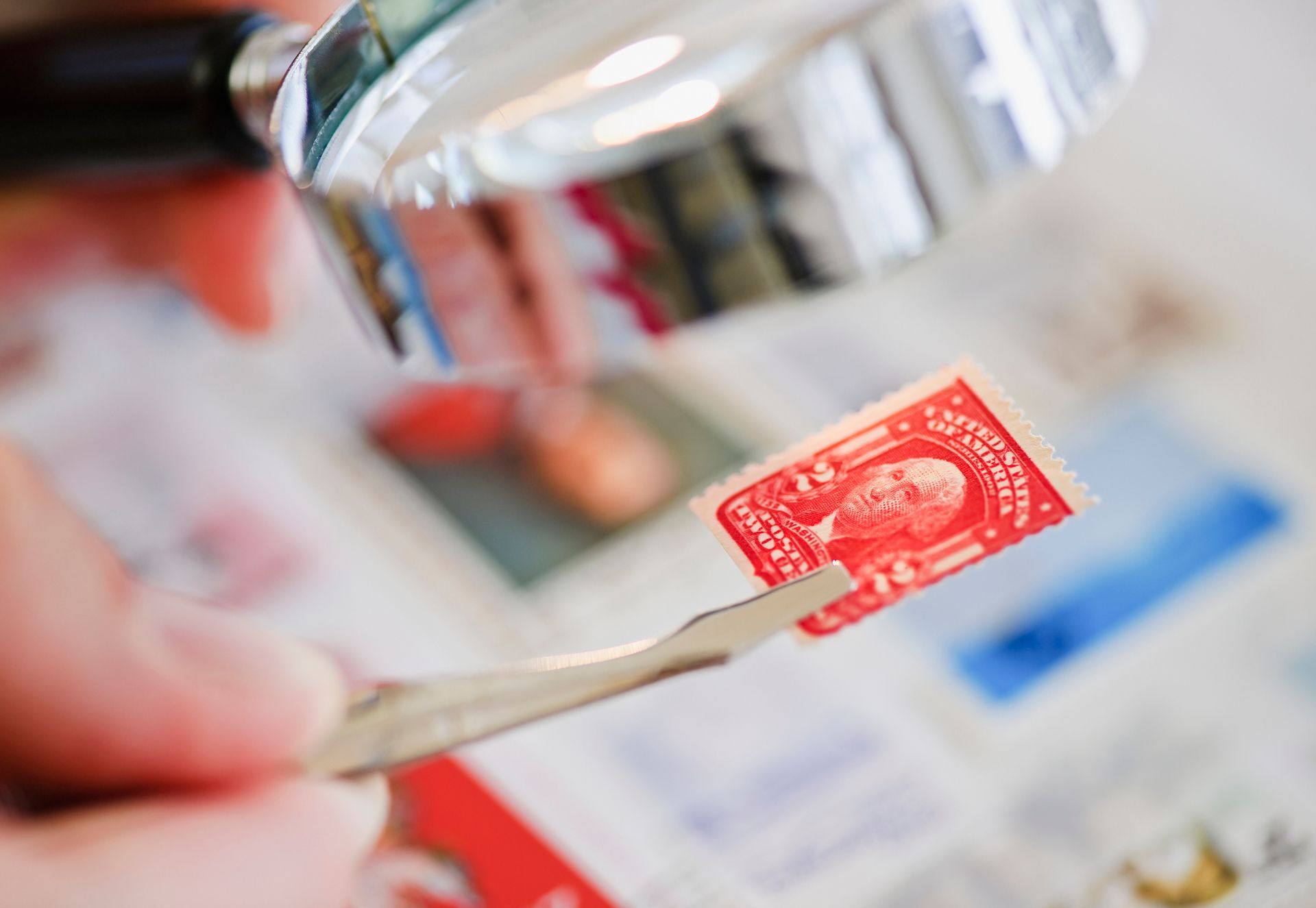 A person is holding a small red stamp with a picture of george washington on it