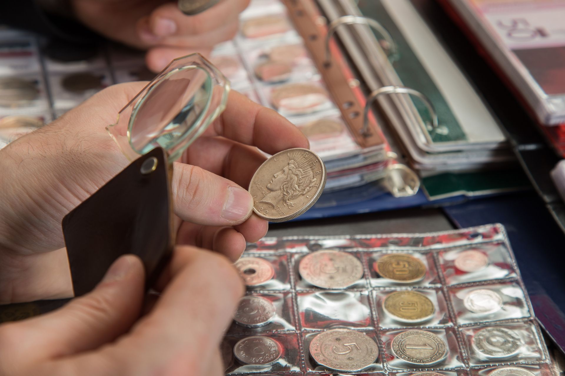 A person is examining a coin with a magnifying glass.