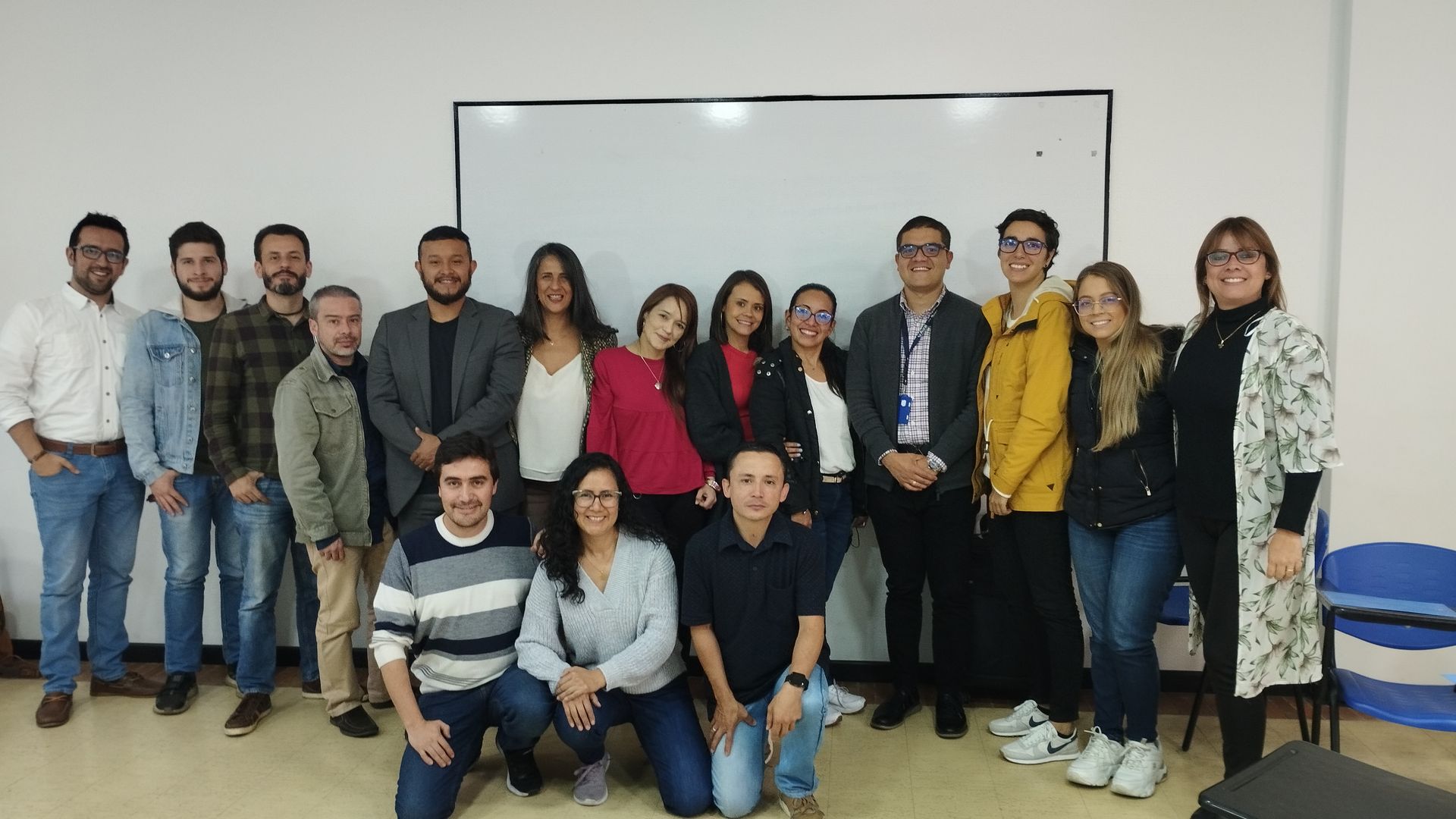 Un grupo de personas posa para una fotografía frente a una pizarra.