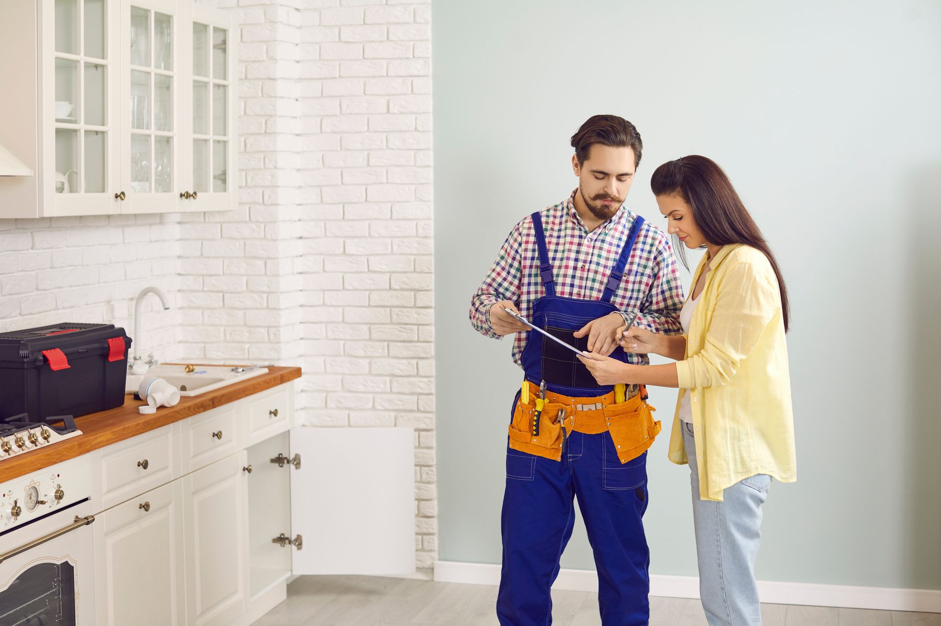 A man and a woman are looking at a tablet in a kitchen.