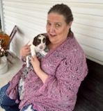 Woman in purple shawl holding a puppy on a porch.